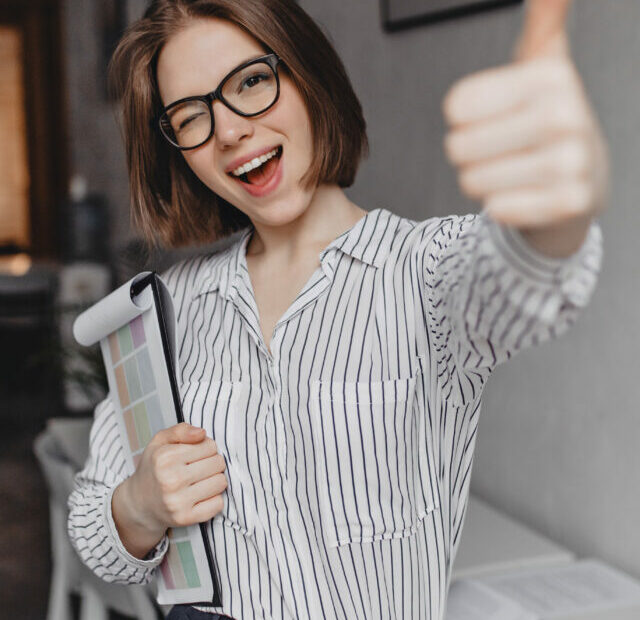 cropped-young-woman-office-style-clothes-glasses-holds-tablet-with-documents-winks-shows-thumb-up.jpg
