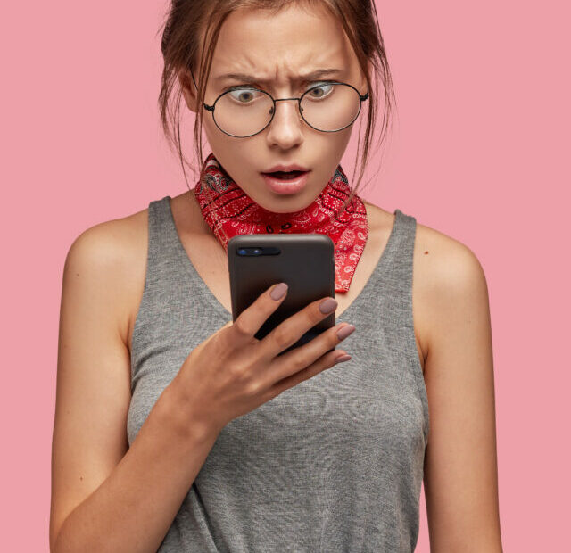 cropped-image-indignant-puzzled-shocked-woman-stares-mobile-phone-1.jpg