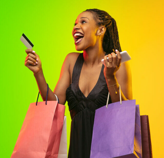cropped-portrait-of-young-woman-in-neon-light-with-shopping-bags-black-friday.jpg