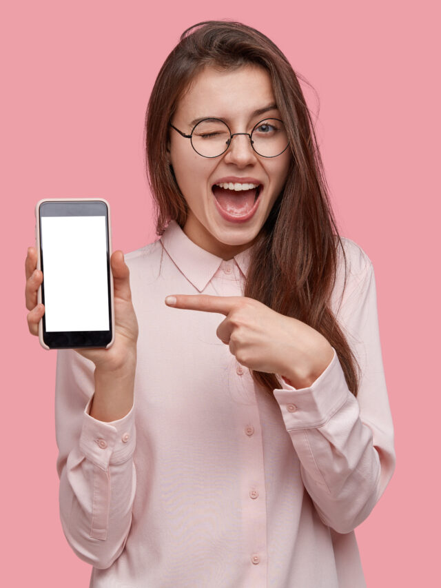 cropped-look-at-this-cell-phone-pleased-happy-woman-blinks-eyes-points-with-index-finger-at-blank-screen-shows-modern-device.jpg